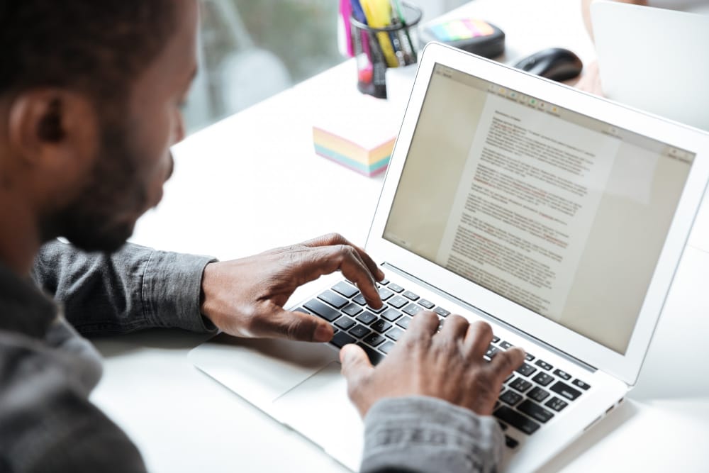 homme en train de taper un manuscrit sur son ordinateur