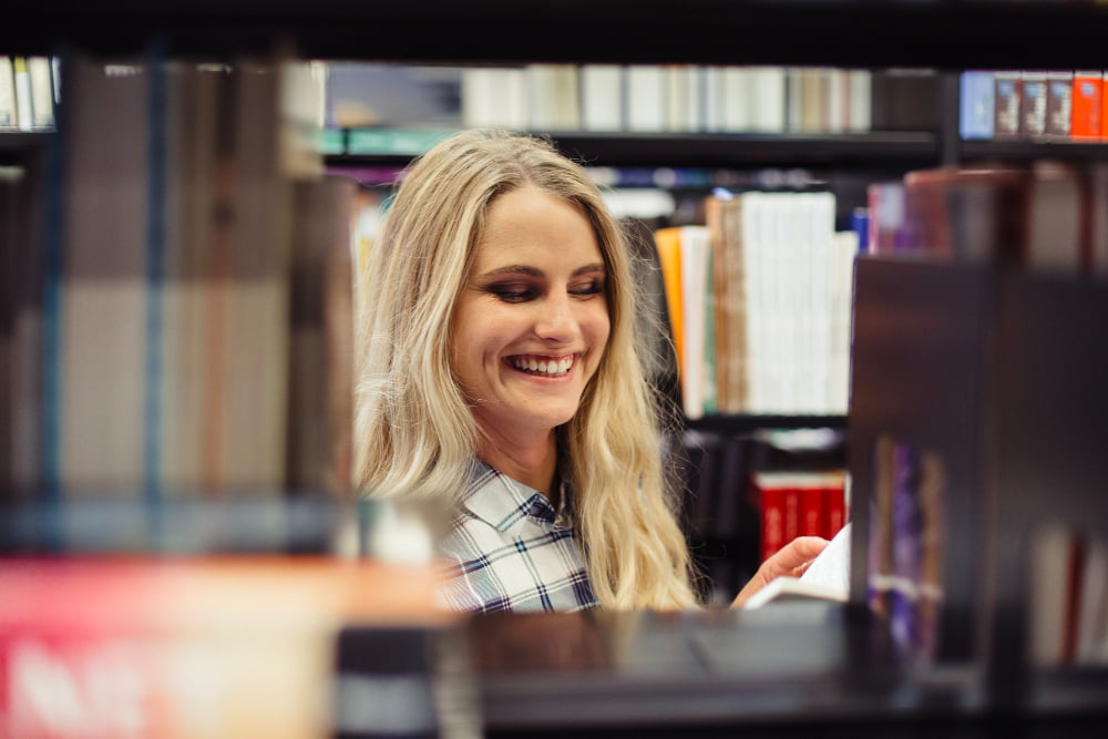 jeune fille souriante dans les allées d'une librairie